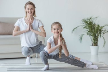 Anne ve kızı pratik yoga birlikte evde