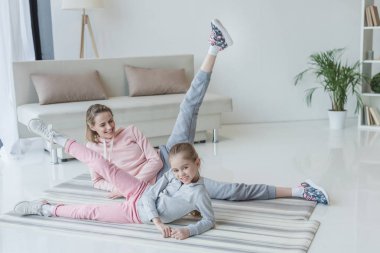 Anne ve kızı evde yoga paspaslar üzerine yalan sırasında bacaklar kaldırma