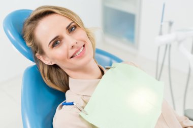 Smiling woman at check-up in modern dental clinic clipart