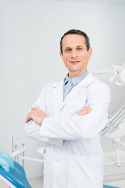 Modern diş Kliniği içinde katlanmış silah ile kendine güvenen doktor