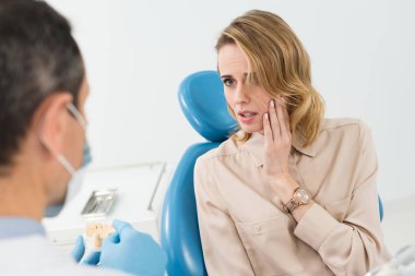 Female patient suffering from toothache in modern dental clinic clipart