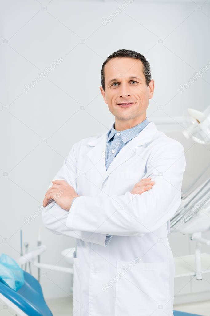 Confident doctor with folded arms in modern dental clinic