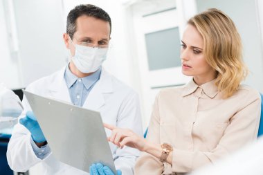 Doktor ve hasta bakarak tanı kayıtlarında modern diş Kliniği gülümseyen