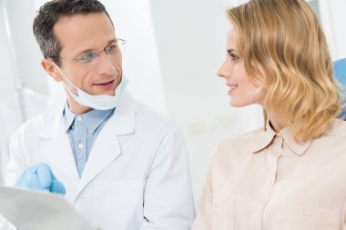 Kadın doktor modern diş Kliniği içinde clipboard işaret ile danışmanlık