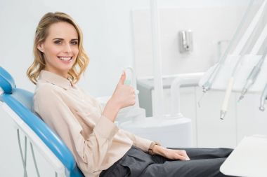 Genç kadın, modern diş Kliniği kontrole başparmak gösterilmesini