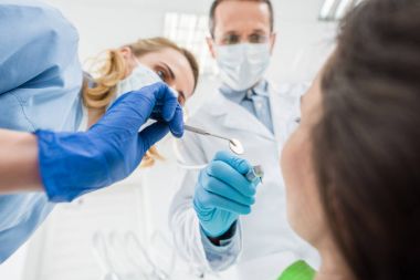 Doktorlar hastanın dişleri ile modern diş Kliniği aynada kontrol