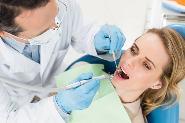 Пациентка на стоматологической процедуре с использованием зубной дрели в современной стоматологической клинике
