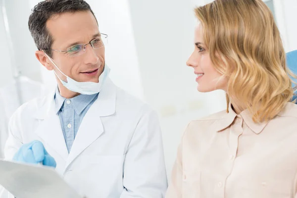 Mujer Consultando Con Médico Señalando Portapapeles Clínica Dental Moderna — Foto de Stock