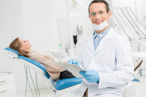 Doctor filling checklist about female patient health in modern dental clinic