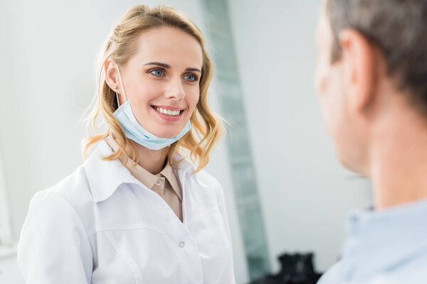 Smiling doctor listening to patient in modern dental clinic