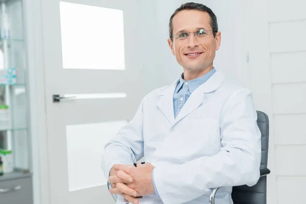 Smiling Doctor Clenched Hands Modern Clinic — Stock Photo, Image