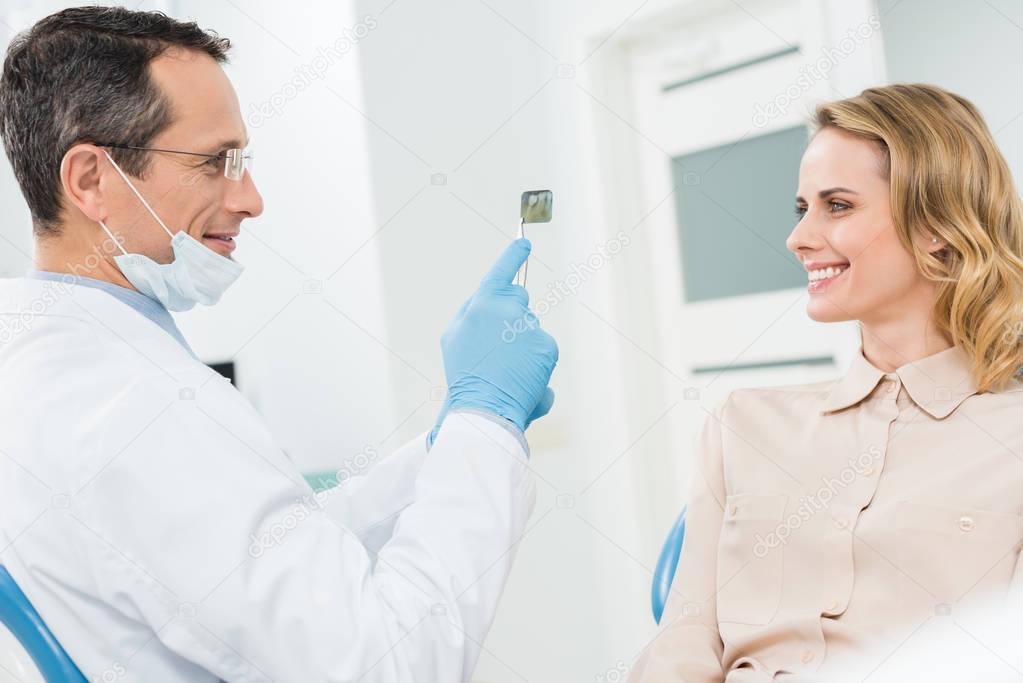Woman consulting with dentist looking at x-ray in modern clinic