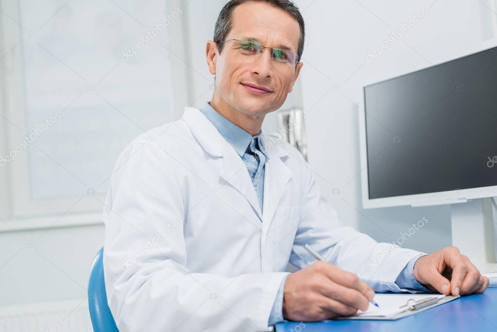 Doctor filling checklist by computer in modern clinic