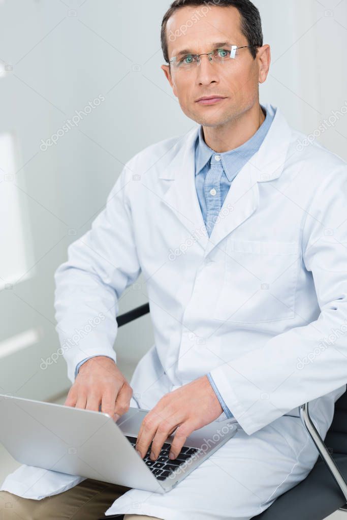 Doctor working by laptop in modern  clinic
