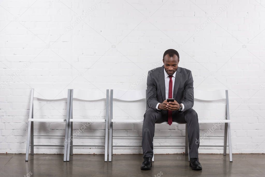 african american businessman with smartphone waiting for job interview