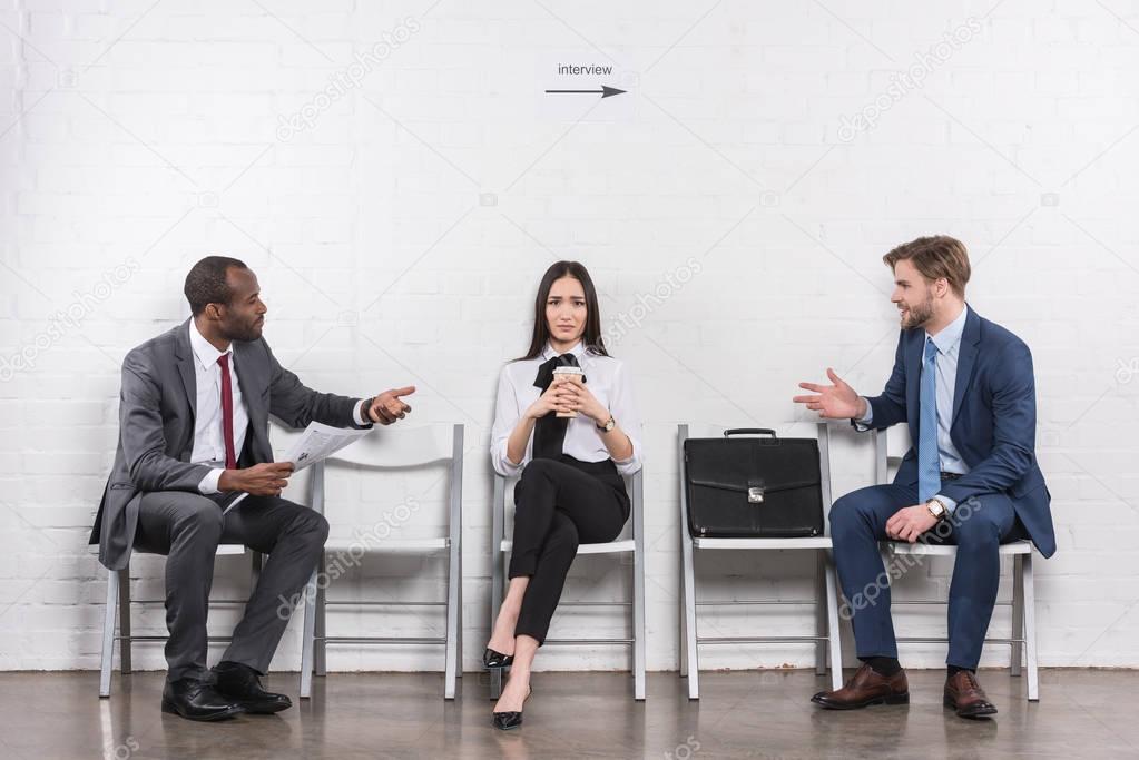 asian businesswoman listening to multicultural businessmen having conversation while waiting for job interview