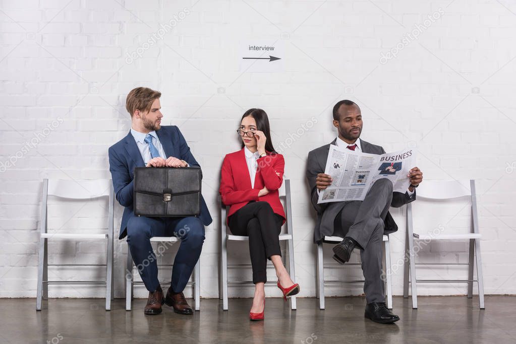 multiethnic business people sitting on chairs while waiting for job interview