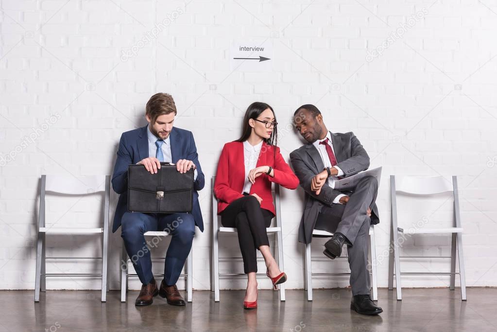 multiethnic business people sitting on chairs while waiting for job interview