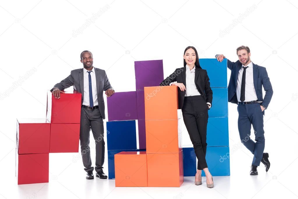 smiling multiethnic business people with colorful blocks isolated on white, teamwork concept