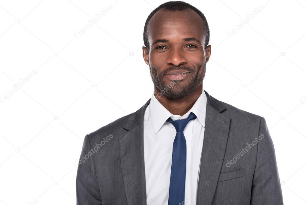 portrait of smiling african american businessman in suit isolated on white