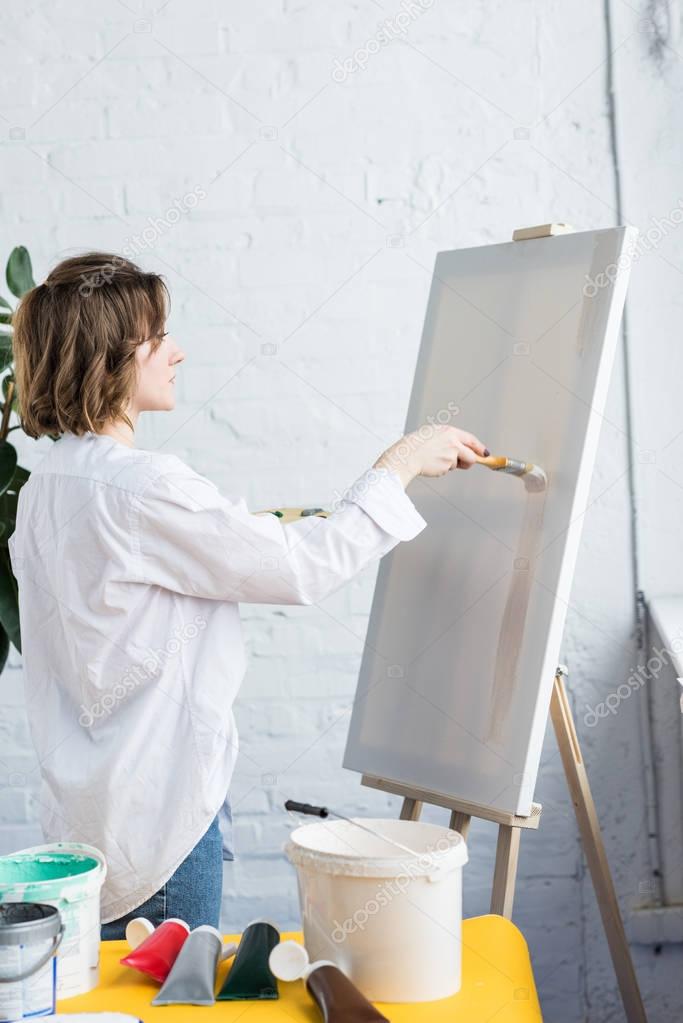 Young creative girl applying artistic primer in light studio