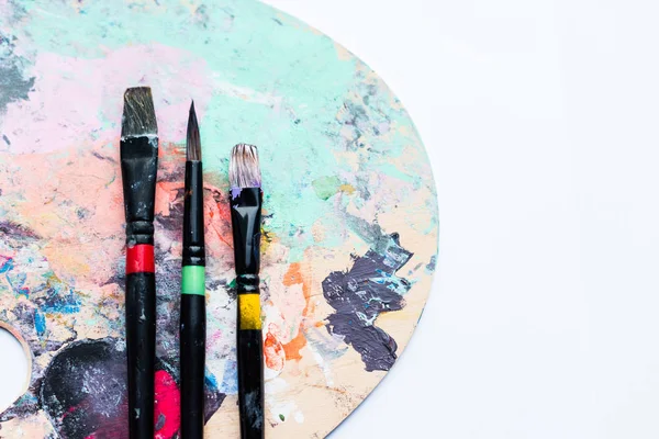 色彩鲜艳的颜料点缀在调色板上的艺术画笔 — 图库照片