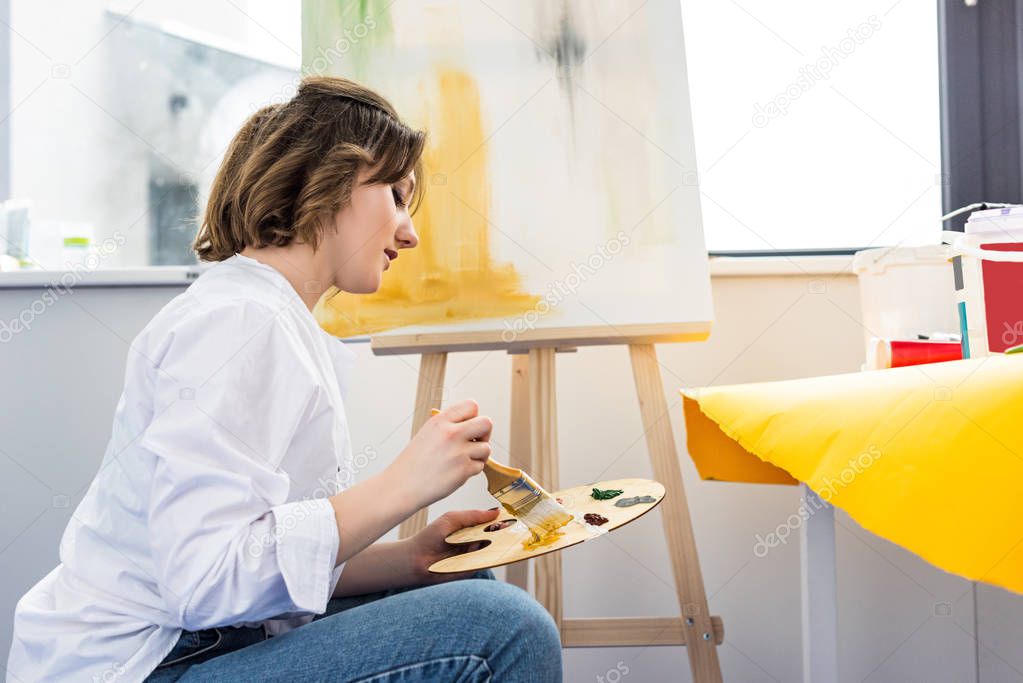 Young inspired girl working with palette in light studio