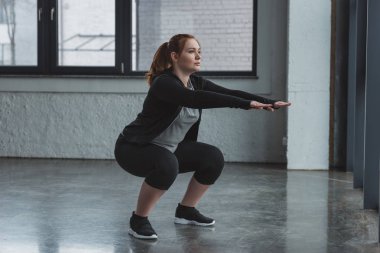 Curvy girl doing squat in gym clipart