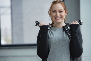 Spor salonunda dumbbells ile eğitim obez gülümseyen kız