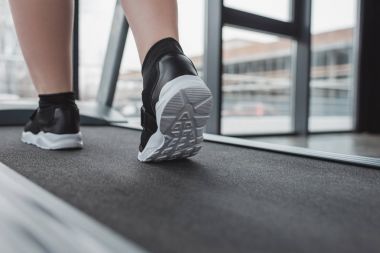Yakın çekim görünümü kilolu kız ayakları üzerinde spor salonunda koşu bandı
