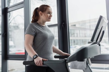 Obez kız spor salonunda koşu bandı üzerinde çalışan