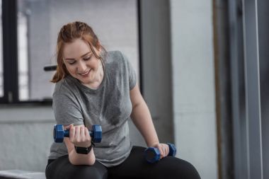 Spor salonunda dumbbells ile eğitim curvy kız