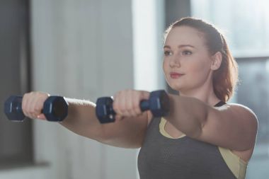 Spor salonunda dumbbells ile eğitim curvy kız