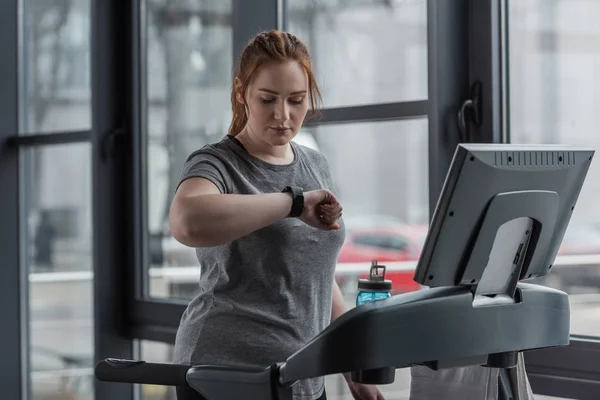 Chica Con Sobrepeso Mirando Rastreador Fitness Mientras Ejecuta Cinta Correr — Foto de Stock