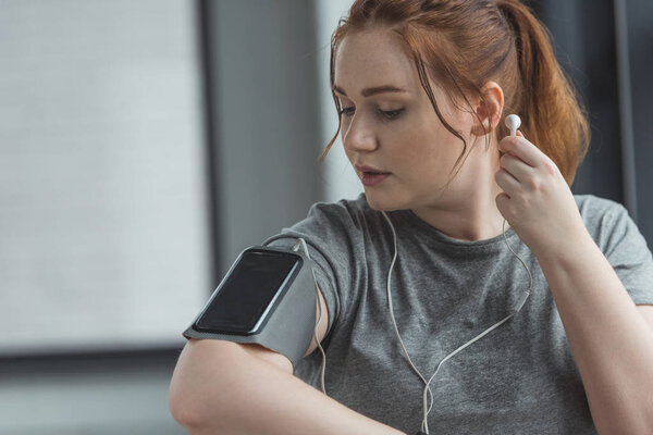 Overweight girl listening to music in gym