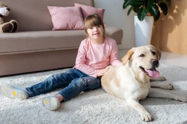 Labrador retriever halı ile katta oturan down Sendromlu Çocuk 