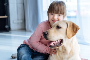 Down sendromu ve Labrador retriever katta oturan çocuk