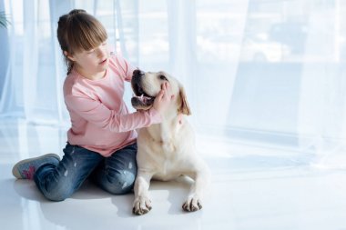 Kid with down syndrome playing with Labrador retriever  clipart