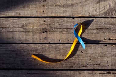 Blue and yellow ribbon as symbol of Down Syndrome Day on wooden background clipart