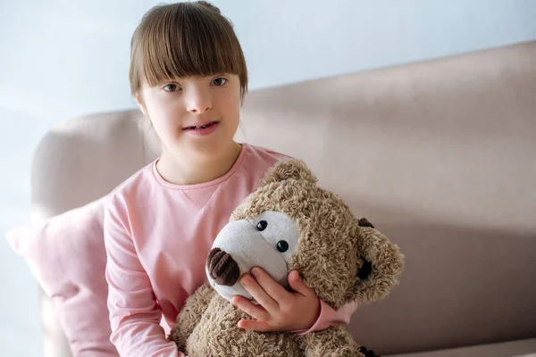 Criança Sorridente Com Síndrome Sentado Sofá Segurando Ursinho Pelúcia — Fotografia de Stock
