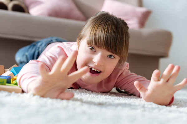 Счастливый ребенок с синдромом пуха лежит на полу в уютной комнате
