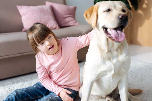 Child with down syndrome stroking Labrador retriever 