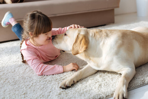 Kid with down syndrome and Labrador retriever touching noses