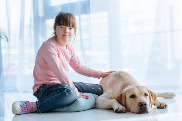 ラブラドル レトリーバー犬が付いている床の上に座ってダウン症子供 — ストック写真