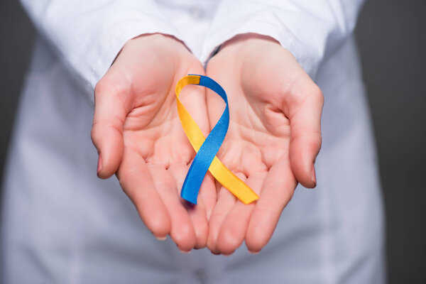 Close-up view of female doctor hands holding Down Syndrome Day ribbon 