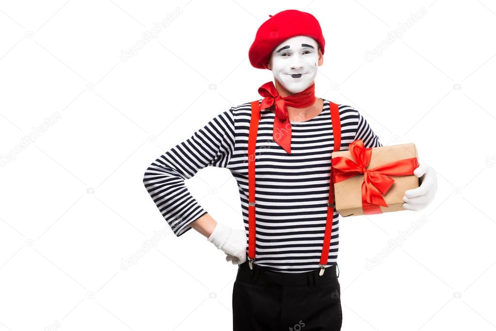smiling mime holding present box and looking at camera isolated on white