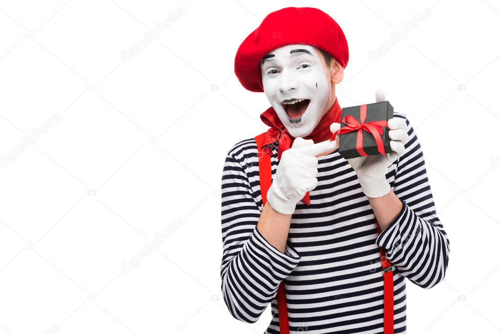 laughing mime pointing on present box isolated on white