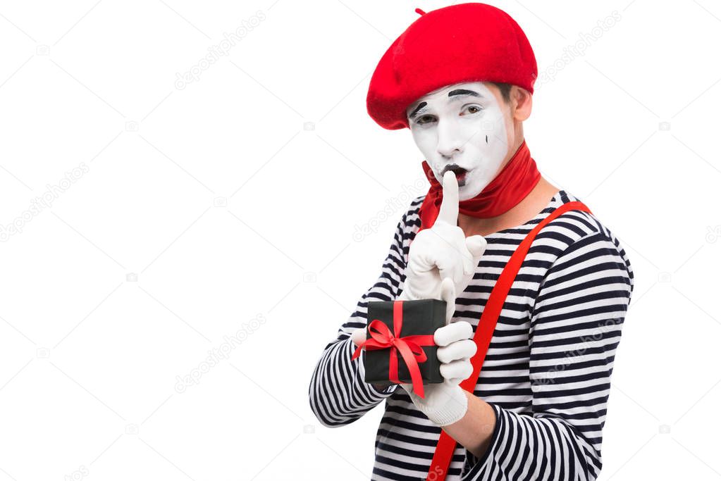 mime holding present box and showing silence gesture isolated on white