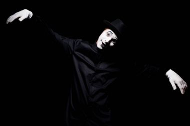 Kameraya bakarak ve siyahta izole kukla gibi davranarak MIME gülümseyen