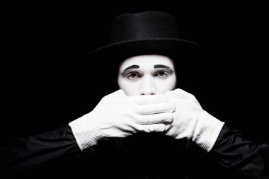 mime covering mouth and looking at camera isolated on black clipart